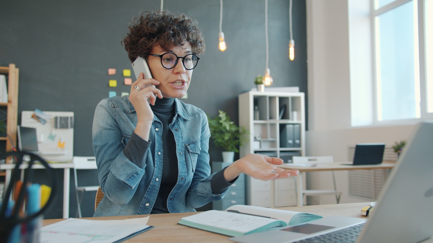 Persona conversando por teléfono en su escritorio