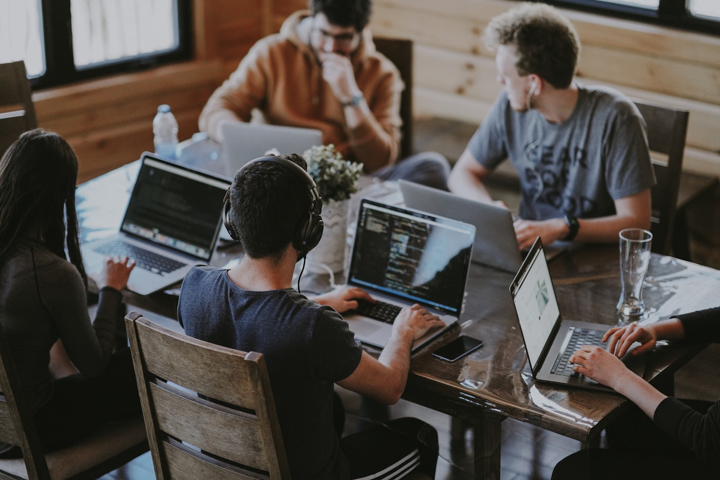 Equipo de trabajo colaborando alrededor de una mesa con notebooks
