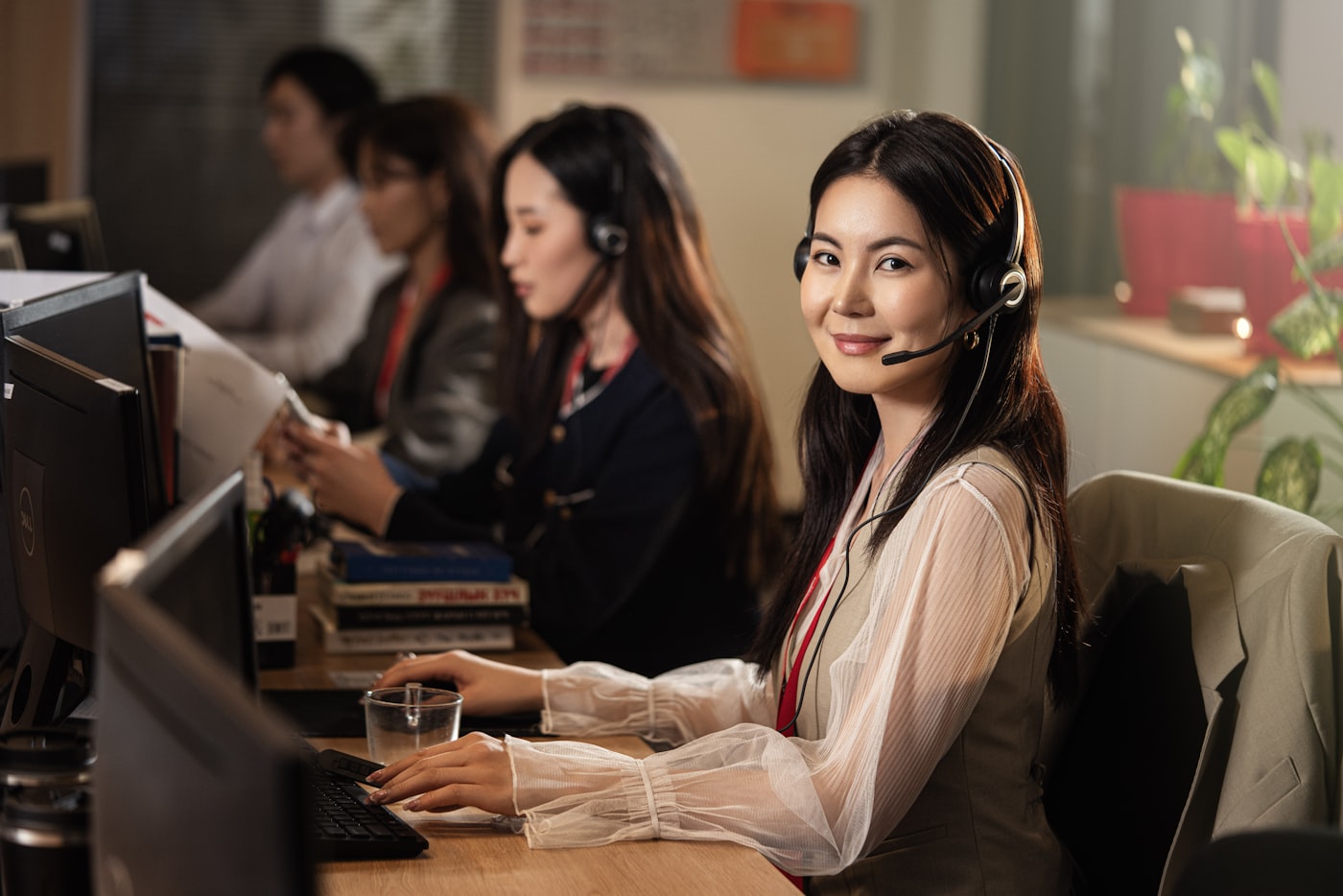 Mujer sonriente con auriculares de soporte frente a un computador